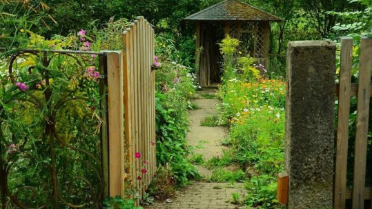 Un portillon en bois est ouvert sur un jardin