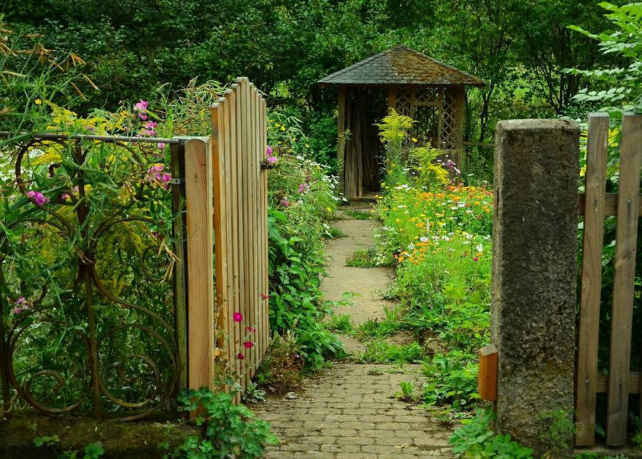Un portillon en bois est ouvert sur un jardin